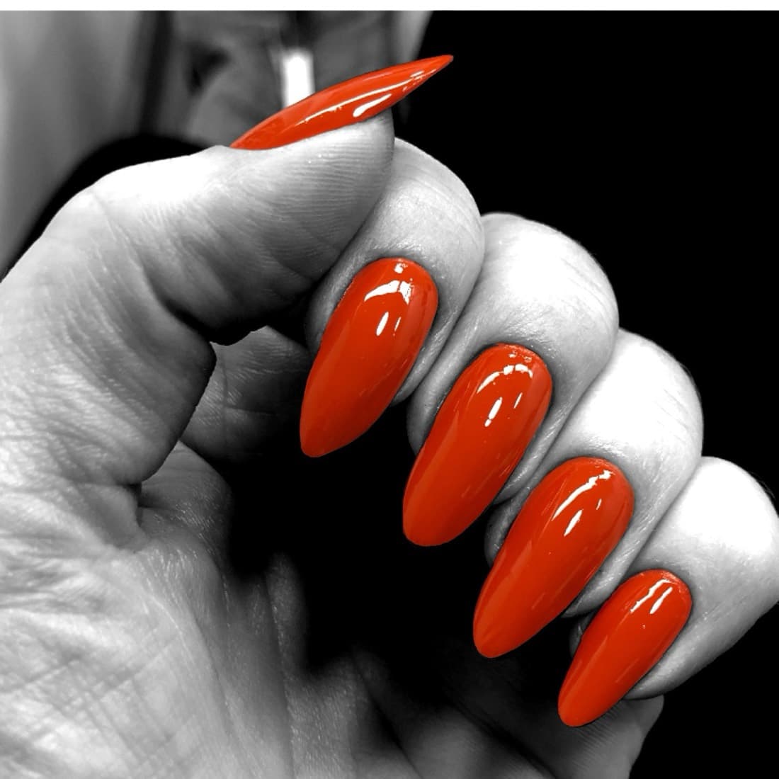 Orange-red stiletto nails sculpted during a manicure at McAllister Spa in Miami Beach