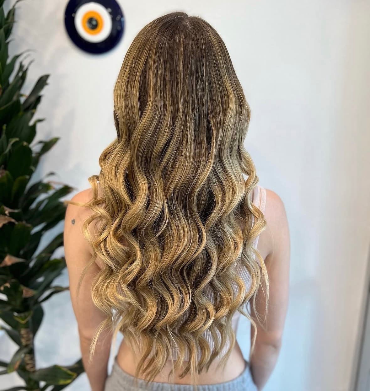 Very long bronde hair in deep, evenly set waves running to the small of the back — hair extensions and balayage by Hali at McAllister Spa in South Beach